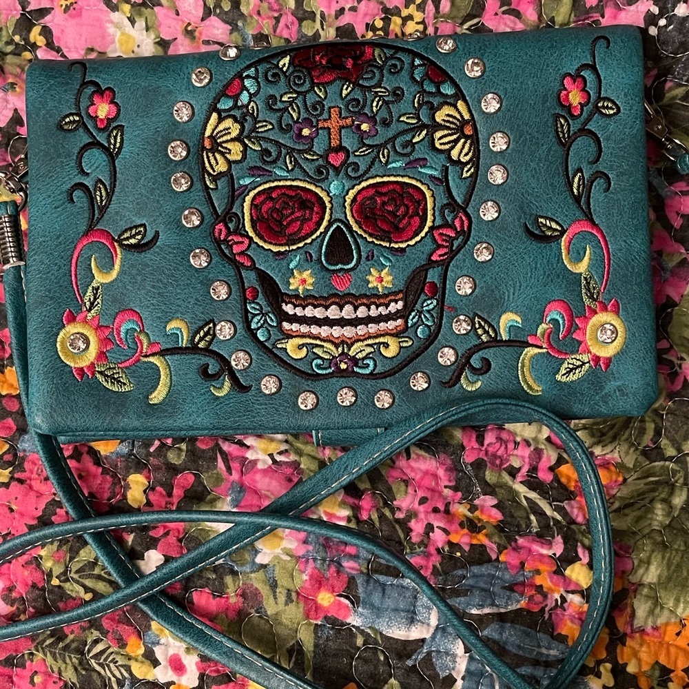 Blue cross body bag, with embroidered sugar skull design.